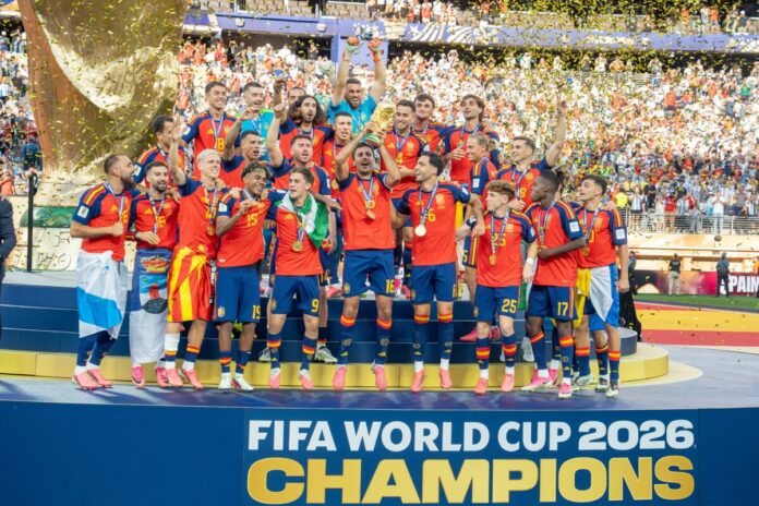 Spain_World_Cup_Winners_Argentina_v_Spain_19_July_2026-1 西班牙隊球員在2026世界盃決賽奪冠後高舉大力神盃慶祝,背景為金色紙屑與看台,前方看板寫著FIFA WORLD CUP 2026